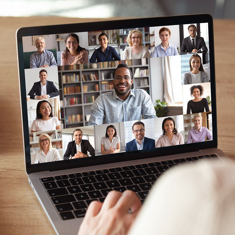 Blick über die Schulter auf einen Team-Call auf einem Laptop.